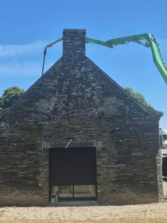 Maçonnerie au pignon d'une longère en pierre, bras de pompe à béton